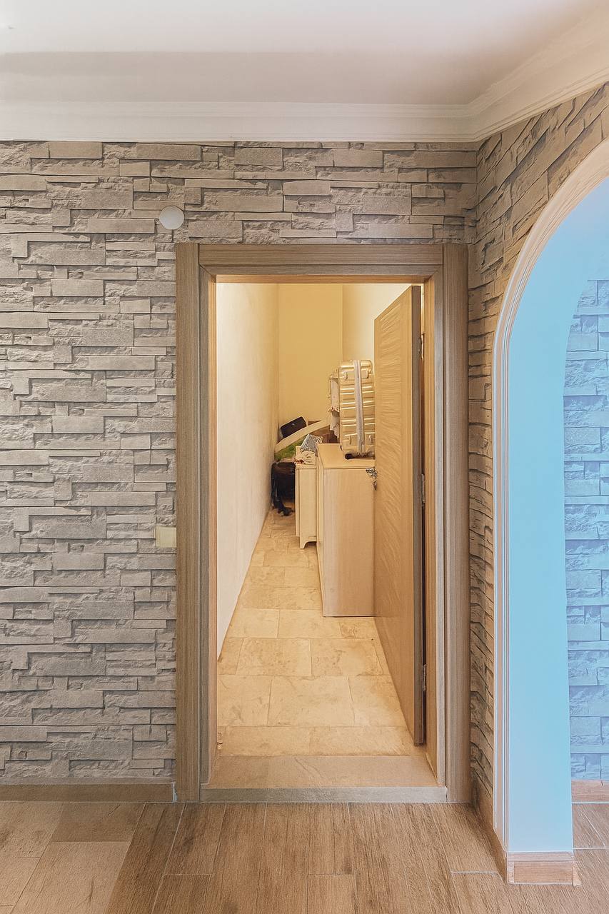Hallway with stone-effect walls, an arched opening and a wooden door in a residence