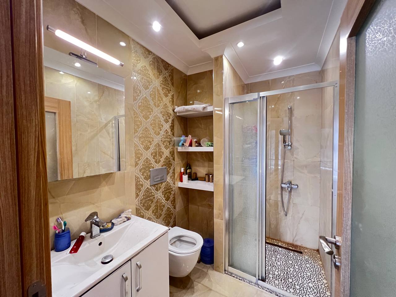 Bathroom with a lit mirror, glass shower and mosaic shower tray in a penthouse