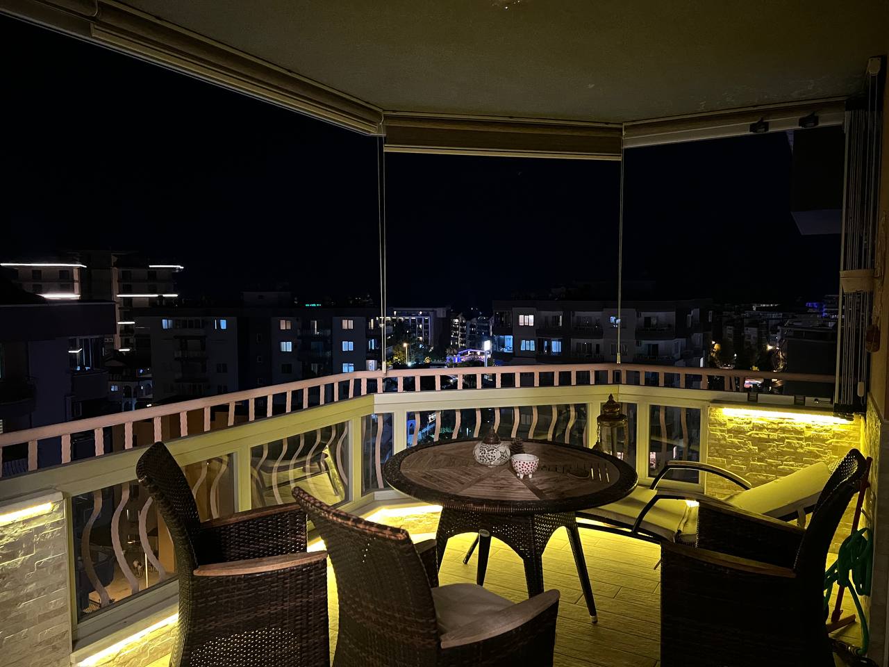 Balcony with wicker chairs and city lights in Tosmur where residences are for sale