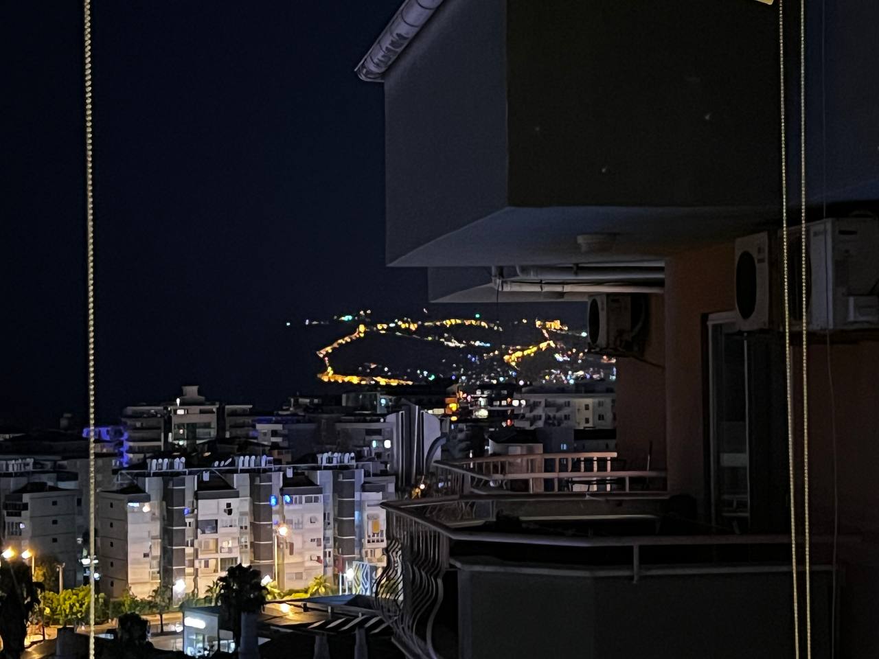 Night city view from a balcony of a top-floor apartment with illuminated buildings
