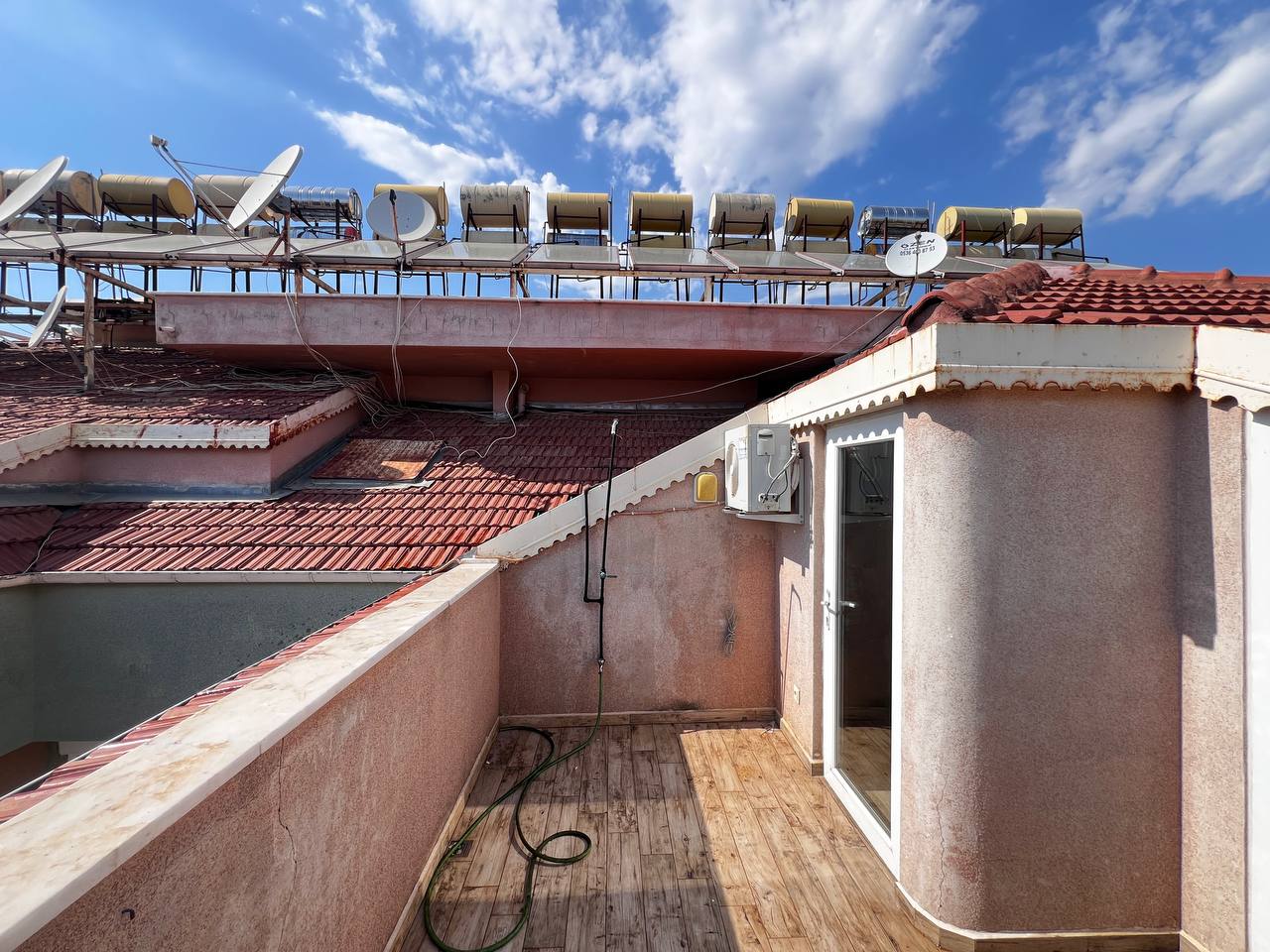 Narrow terrace with timber decking and solar water heaters of a duplex in Turkey