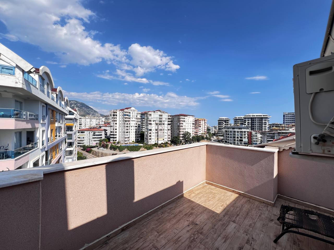 Corner terrace with timber decking and views of residential buildings from a residence