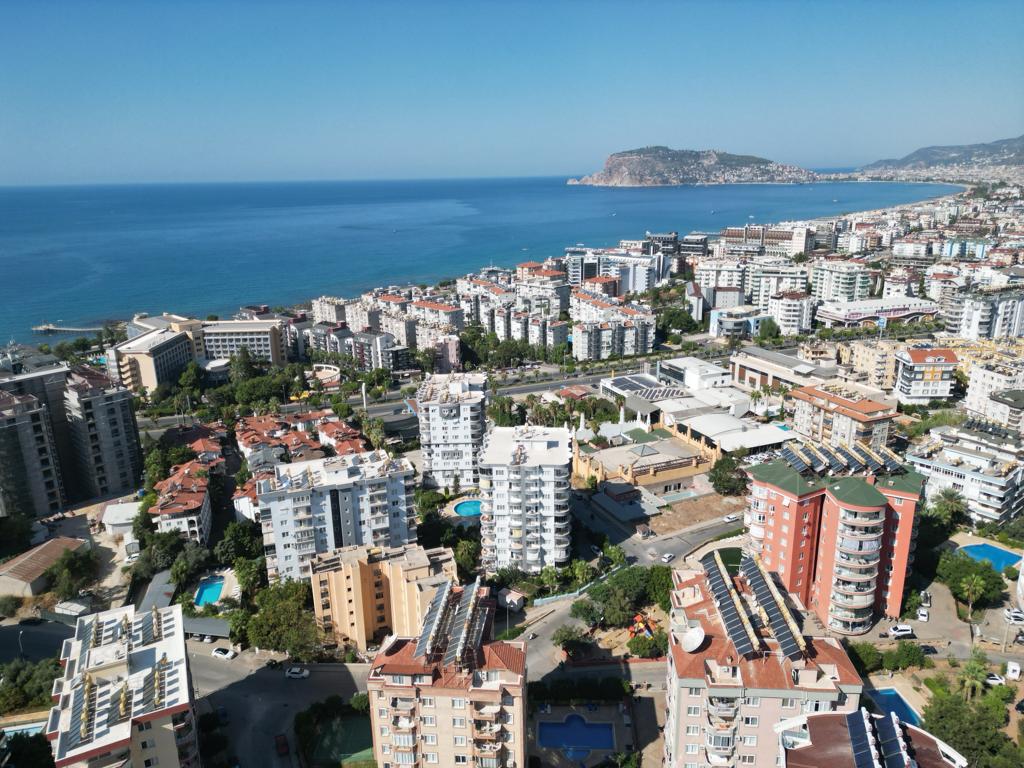 Aerial view of city blocks, a bay and open sea with homes for sale in Turkey