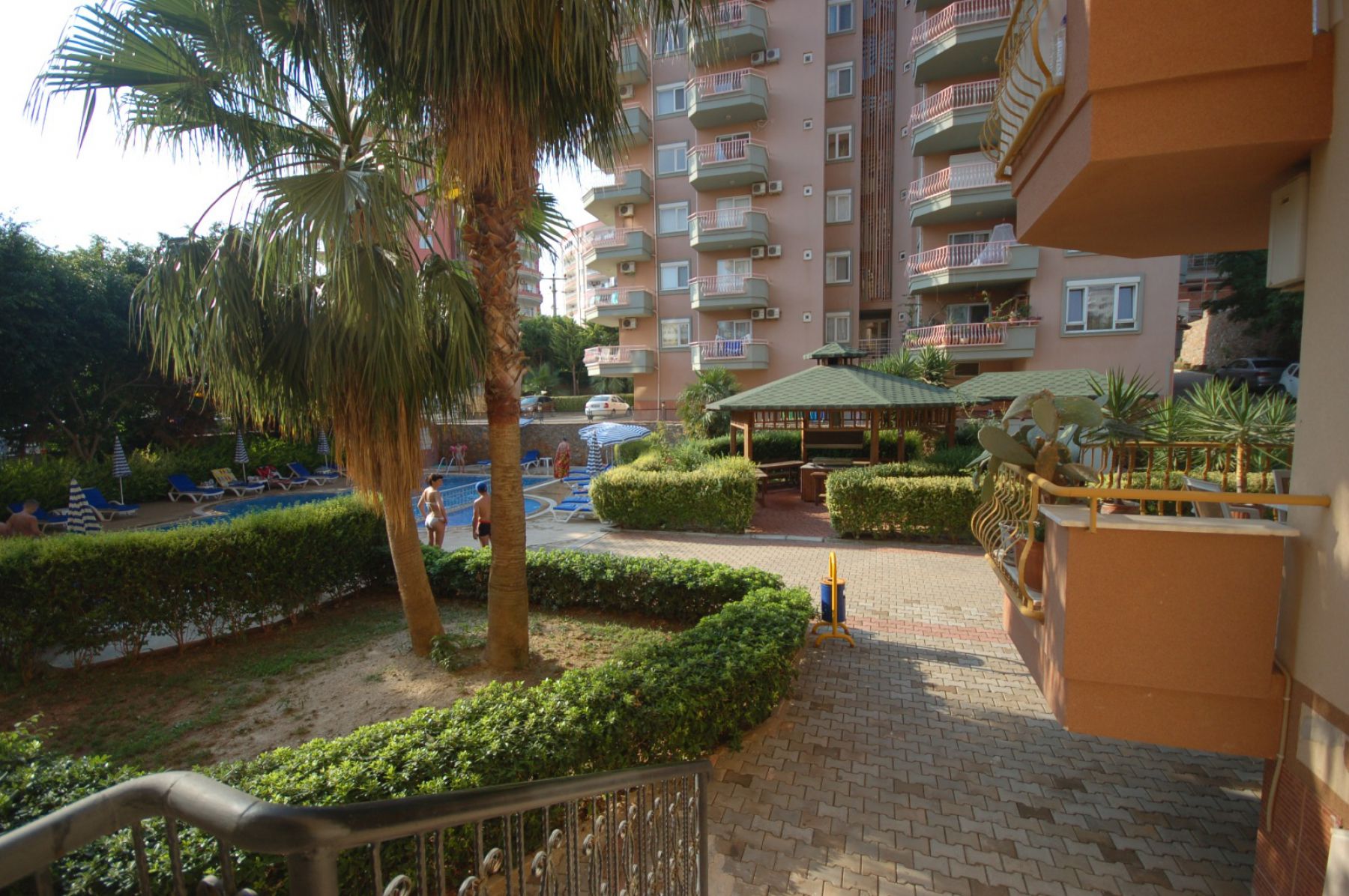 Palm-lined path and outdoor pool in a complex where residences are for sale