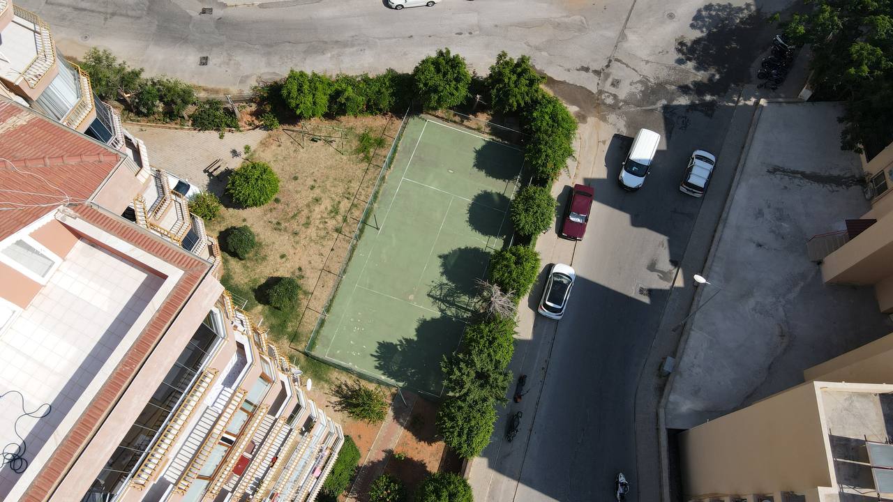 Tennis court beside residential buildings in a complex with apartments for sale in Turkey